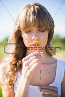 Pensive young woman smelling flower