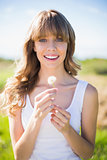 Smiling young woman holding dandelion