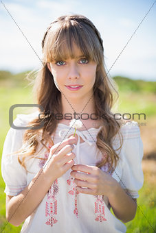Peaceful young woman holding dandelion