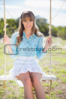 Cheerful young model posing while sitting on swing