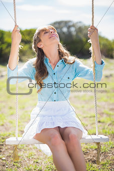 Young model relaxing while sitting on swing