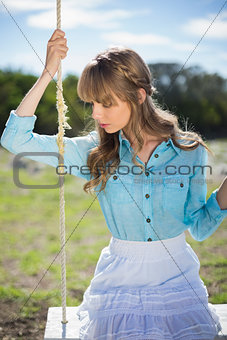 Pretty young model relaxing sitting on swing