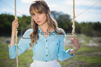 Mysterious young model relaxing sitting on swing