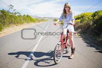Cheerful young model posing while riding bike