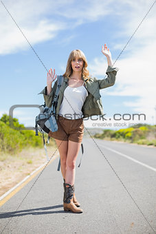 Sexy blonde making gesture while hitchhiking