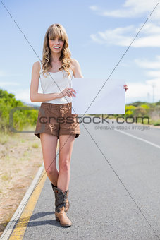 Cheerful woman holding sign while hitchhiking