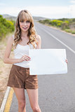 Attractive blonde holding sign while hitchhiking