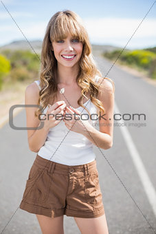 Smiling pretty woman holding flower while walking on the road