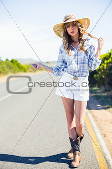 Trendy attractive blonde hitchhiking at the roadside