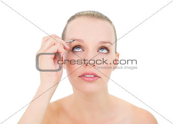 Concentrated pretty blonde model plucking her eyebrows