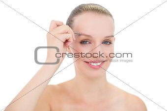 Amused pretty blonde model plucking her eyebrows
