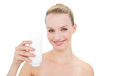 Delighted pretty blonde model toasting the camera with a glass of milk