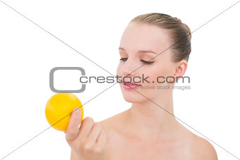 Pensive pretty blonde model looking at an orange