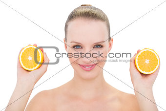 Joyful pretty blonde model showing two orange halves