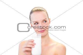 Pensive pretty blonde model holding a glass of milk