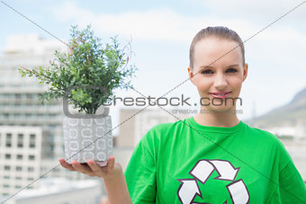 Happy pretty environmental activist showing a plant