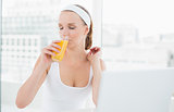 Natural pretty sportswoman enjoying orange juice