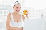 Content pretty sportswoman holding a glass of orange juice