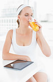 Peaceful pretty sportswoman drinking orange juice