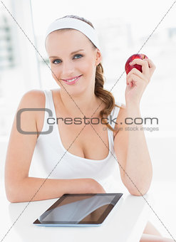 Cheerful pretty sportswoman holding an apple