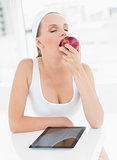 Relaxed pretty sportswoman eating an apple