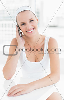 Pleased pretty sportswoman answering a phone call