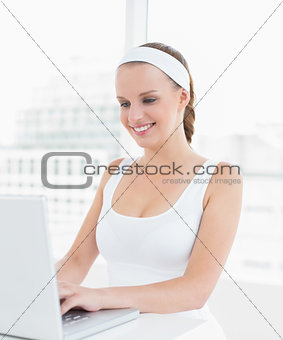Relaxed pretty sportswoman typing on a laptop