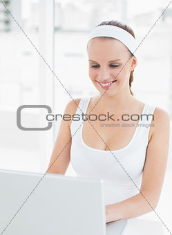 Joyful pretty sportswoman using a laptop