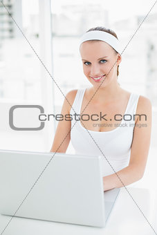 Pleased pretty sportswoman using a laptop