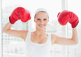 Successful pretty sportswoman raising her boxing gloves