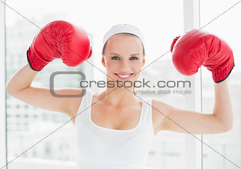 Successful pretty sportswoman raising her boxing gloves