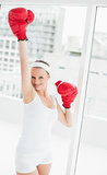 Cheering pretty sportswoman raising her boxing glove