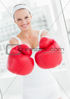 Laughing pretty sportswoman showing her boxing gloves
