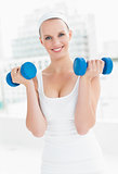 Motivated pretty sportswoman carrying dumbbells