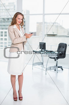 Content pretty businesswoman holding a mobile phone