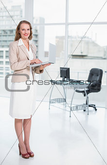Smiling pretty businesswoman holding laptop