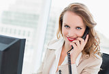 Cheerful pretty businesswoman answering a phone call