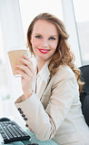 Smiling pretty businesswoman having a cup of coffee