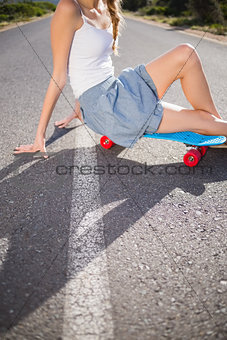 Body of young woman sitting on her skateboard