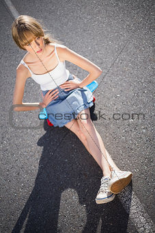 Trendy young woman sitting on her skateboard