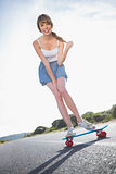Cheerful young woman balancing on her skateboard