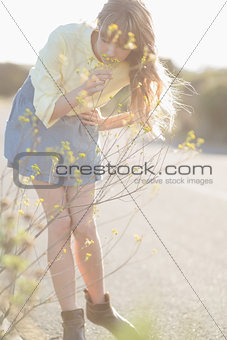 Peaceful hipster girl smelling flowers