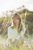 Blonde hipster girl sitting on the grass looking at camera
