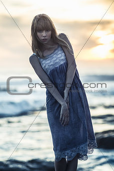 Beautiful young model standing on rocks by the sea
