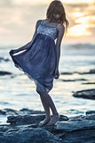 Beautiful young woman standing on rocks by the sea