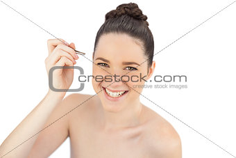 Smiling sensual model using tweezers