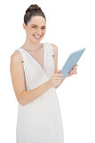 Cheerful young model in white dress holding tablet pc