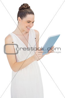 Smiling young model in white dress holding tablet pc