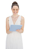 Happy young model in white dress holding tablet pc