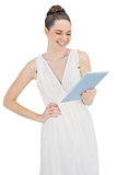 Smiling young model in white dress holding tablet computer